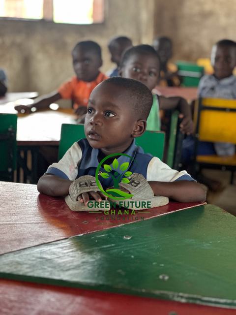 A young boy seated at a green and red desk, looking to the side